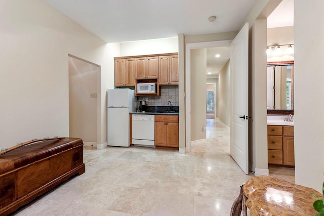 kitchen featuring a sink, baseboards, white appliances, and backsplash