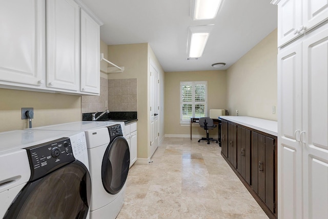 washroom featuring baseboards, cabinet space, and independent washer and dryer