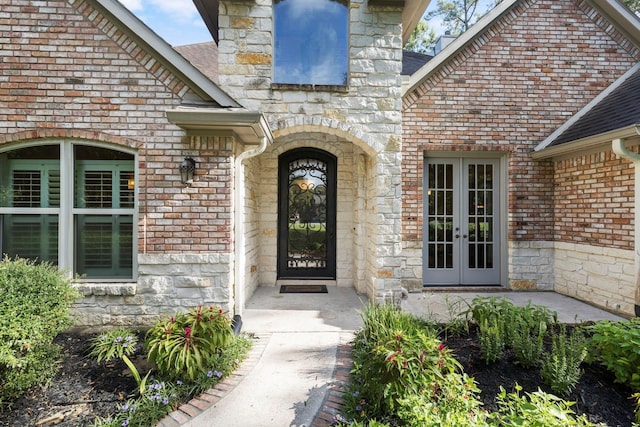 entrance to property with french doors, stone siding, and brick siding