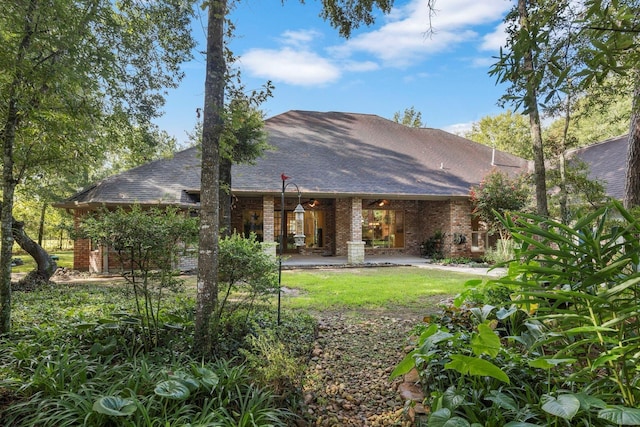 rear view of house with a patio, brick siding, and a shingled roof