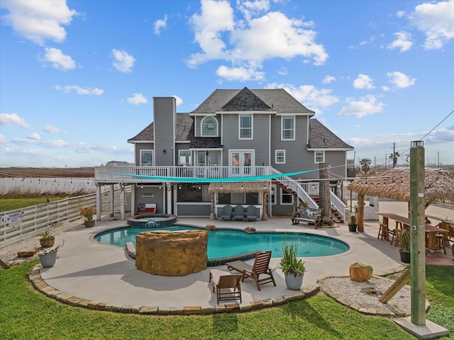 rear view of house with a patio, stairway, fence, and a pool with connected hot tub