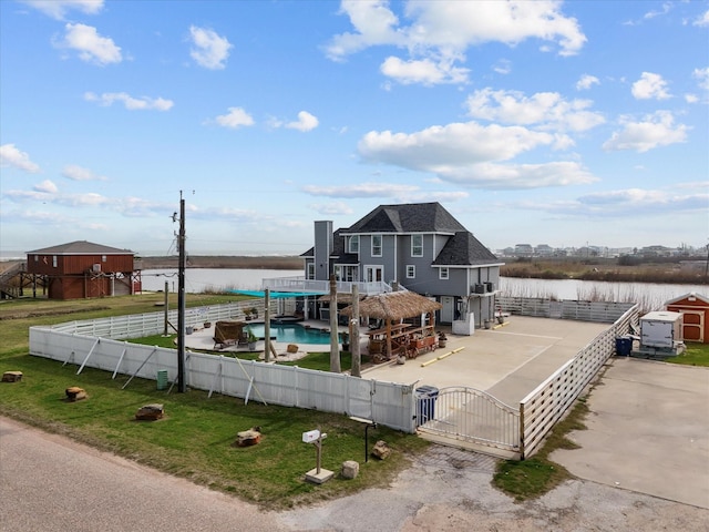 back of house with a gate, a lawn, a water view, and a fenced front yard