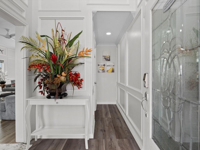interior space with crown molding, a decorative wall, and dark wood-style floors