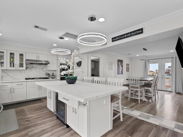 kitchen with ornamental molding, white cabinets, visible vents, and dark wood-style floors