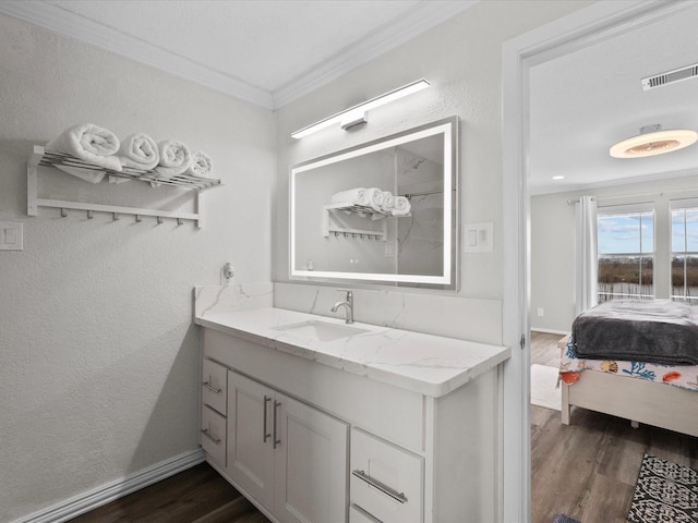 bathroom with baseboards, ornamental molding, visible vents, vanity, and wood finished floors