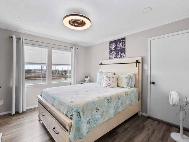 bedroom with baseboards, crown molding, and wood finished floors