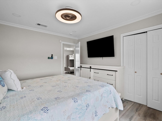 bedroom featuring crown molding, visible vents, wood finished floors, and a closet