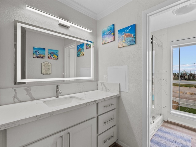 full bath featuring a stall shower, vanity, ornamental molding, and a textured wall