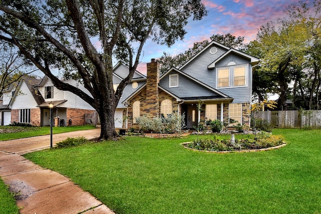 view of front of property featuring stone siding, a lawn, a chimney, and fence