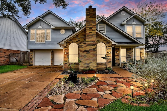 view of front of house featuring stone siding, fence, concrete driveway, an attached garage, and a chimney