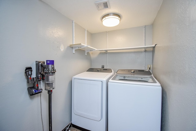 washroom with washer and dryer, laundry area, a textured wall, and visible vents