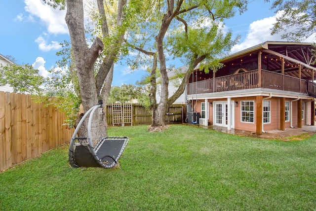 view of yard with central AC unit, french doors, and a fenced backyard