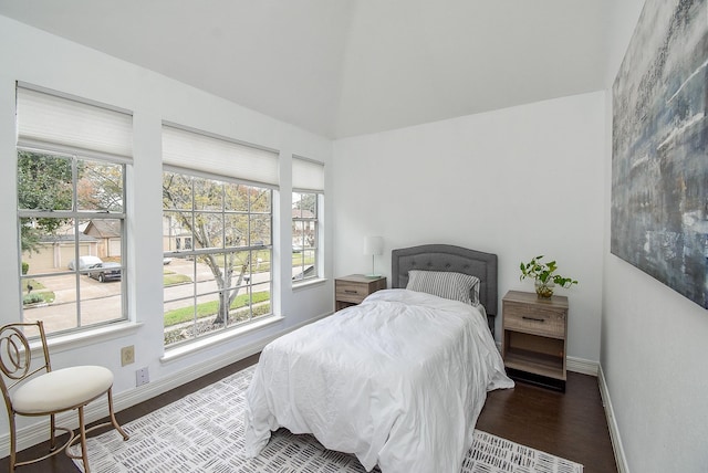 bedroom featuring lofted ceiling, multiple windows, wood finished floors, and baseboards