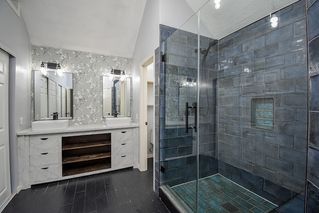 bathroom with a shower stall, toilet, double vanity, vaulted ceiling, and wood finished floors