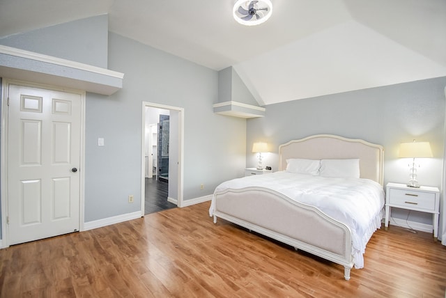 bedroom with baseboards, lofted ceiling, and wood finished floors