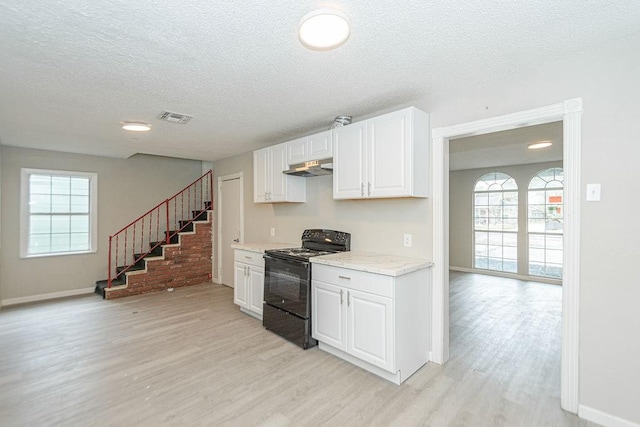 kitchen with visible vents, black range with electric stovetop, under cabinet range hood, light countertops, and white cabinetry