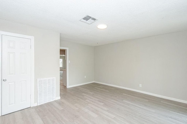 unfurnished room with visible vents, baseboards, a textured ceiling, and light wood-style flooring