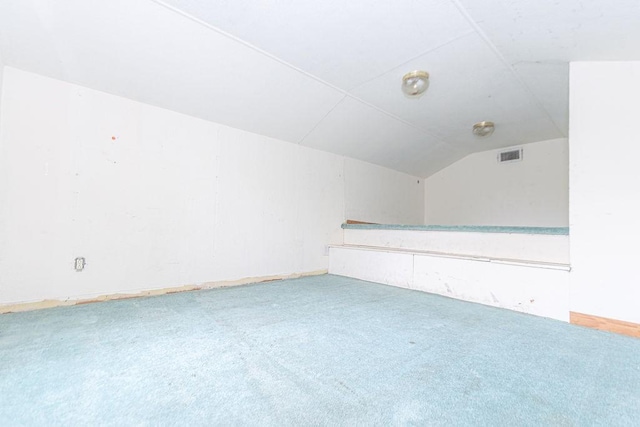 additional living space with visible vents, lofted ceiling, and carpet