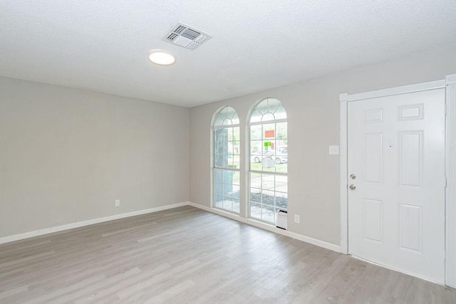 foyer featuring light wood finished floors, visible vents, and a textured ceiling