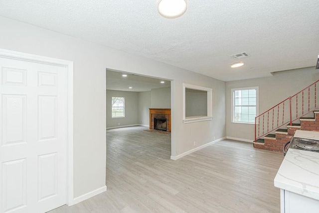 interior space with visible vents, stairway, light wood-style floors, a fireplace, and baseboards