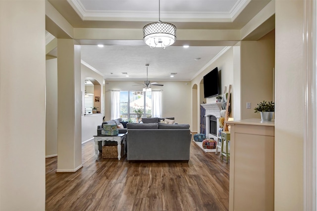 living room featuring ceiling fan, dark wood-style flooring, a fireplace, and ornamental molding