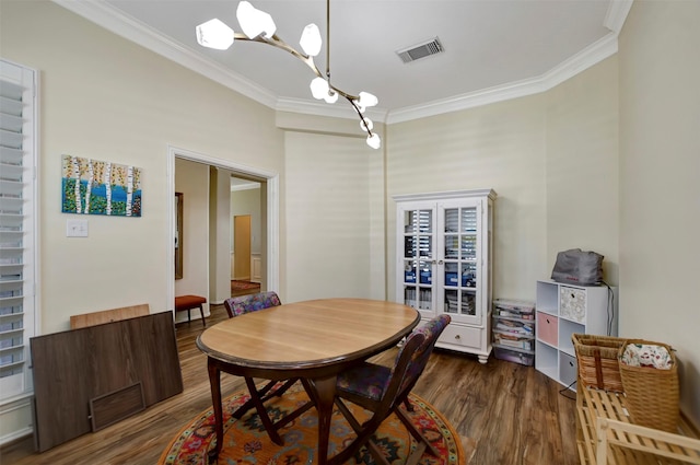 dining area with an inviting chandelier, crown molding, wood finished floors, and visible vents