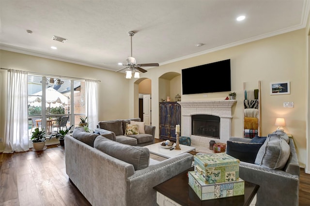 living room featuring arched walkways, visible vents, crown molding, and wood finished floors