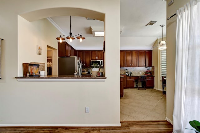 kitchen with visible vents, backsplash, decorative light fixtures, arched walkways, and stainless steel appliances