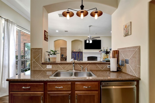 kitchen featuring a ceiling fan, a sink, stainless steel dishwasher, open floor plan, and a fireplace