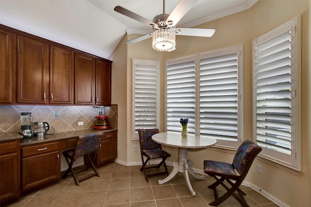 dining area featuring baseboards, ceiling fan, lofted ceiling, light tile patterned floors, and built in study area