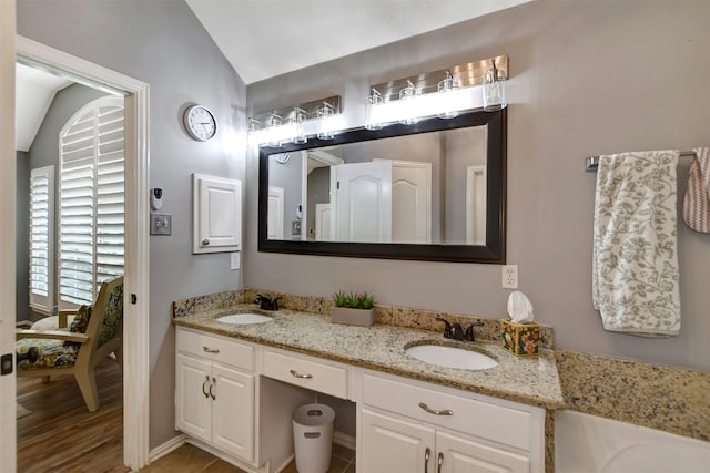 bathroom with lofted ceiling, double vanity, and a sink