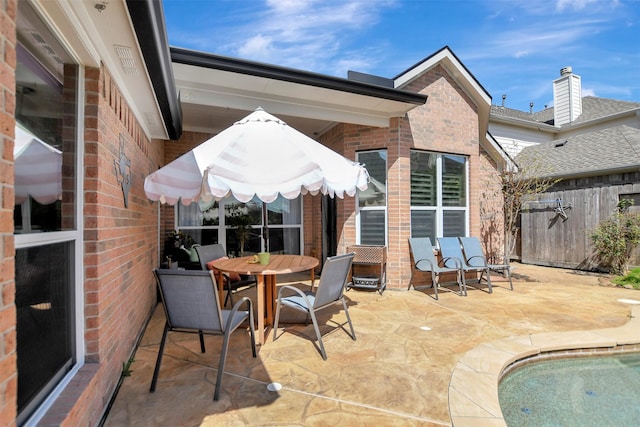 view of patio / terrace with outdoor dining space, fence, and an outdoor pool