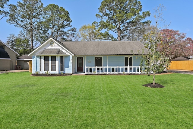 ranch-style house featuring covered porch, a shingled roof, a front yard, and fence