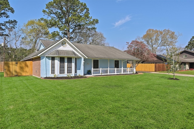 rear view of property featuring covered porch, a lawn, a shingled roof, and fence