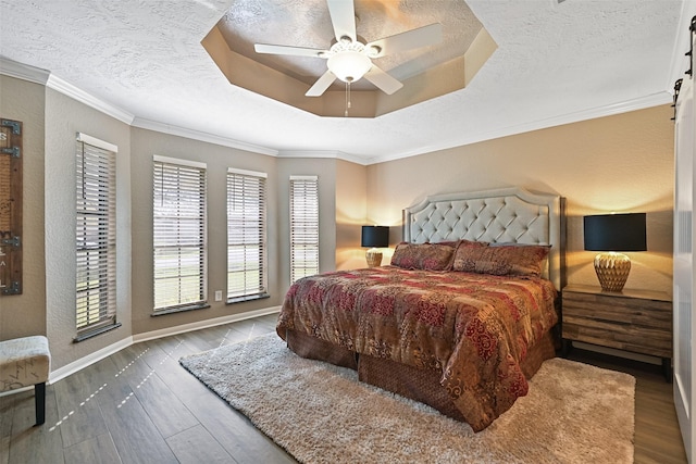 bedroom featuring a textured ceiling, crown molding, a tray ceiling, and wood finished floors