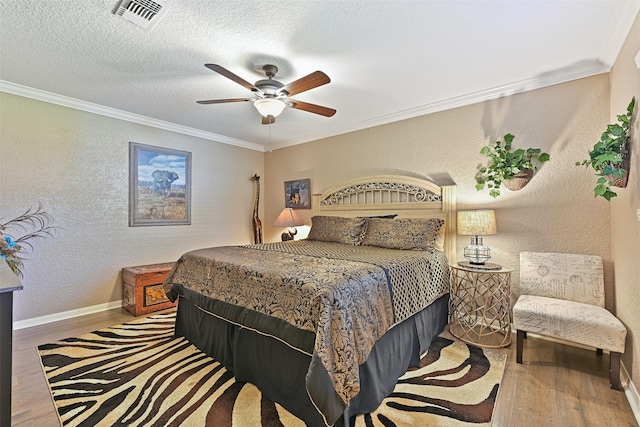 bedroom with visible vents, ornamental molding, and a textured wall