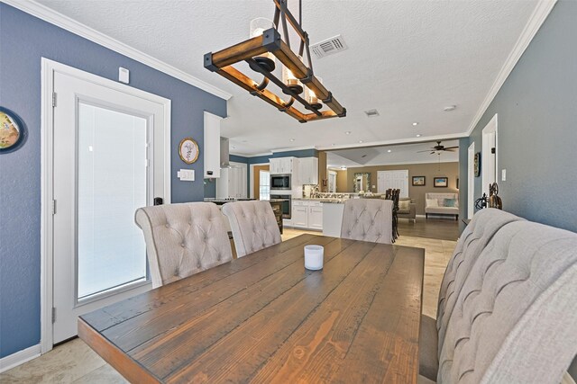 dining room with a ceiling fan, visible vents, light wood finished floors, ornamental molding, and a textured ceiling