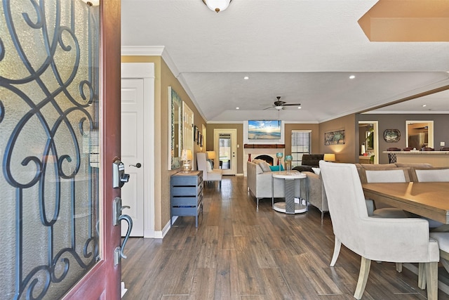 entryway featuring dark wood-type flooring, ceiling fan, a lit fireplace, ornamental molding, and recessed lighting