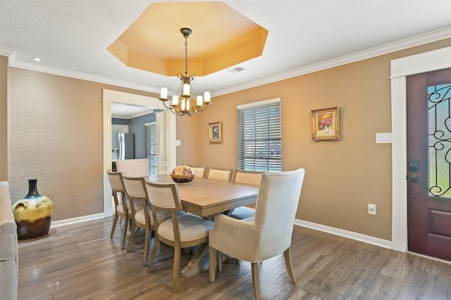 dining room with a tray ceiling, a notable chandelier, wood finished floors, and baseboards