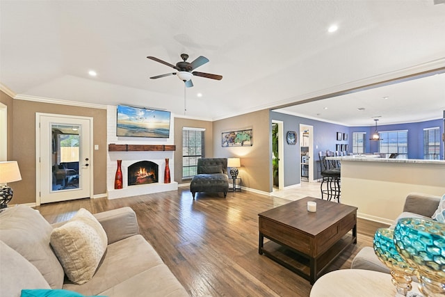 living room with ornamental molding, light wood-style floors, baseboards, and ceiling fan