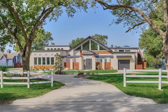 view of front of property with brick siding, a front lawn, fence, a garage, and driveway