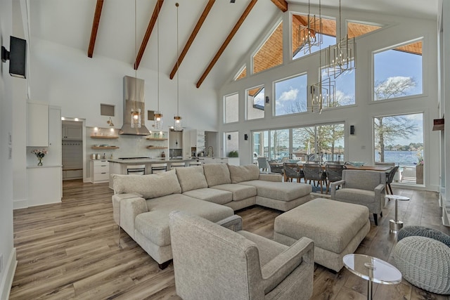 living area with beamed ceiling, a notable chandelier, light wood-type flooring, and high vaulted ceiling