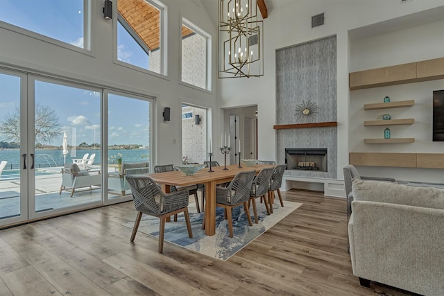 dining space featuring wood finished floors, visible vents, a fireplace, a water view, and a chandelier