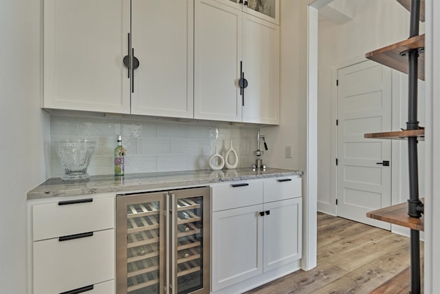 bar with wine cooler, a dry bar, backsplash, and light wood finished floors