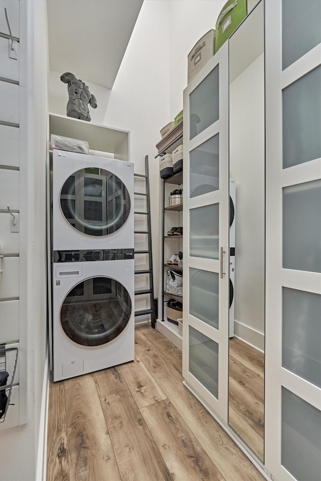 laundry area with light wood-style floors, laundry area, and stacked washing maching and dryer