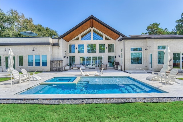 back of house featuring a patio area, brick siding, and a pool with connected hot tub