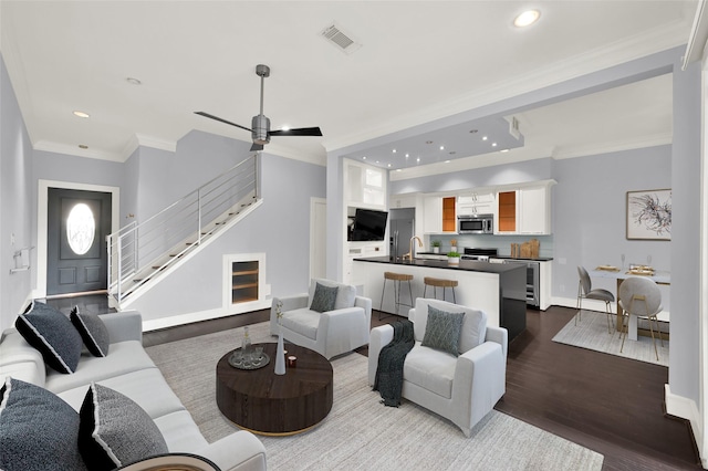 living room featuring stairway, dark wood-type flooring, visible vents, and ornamental molding