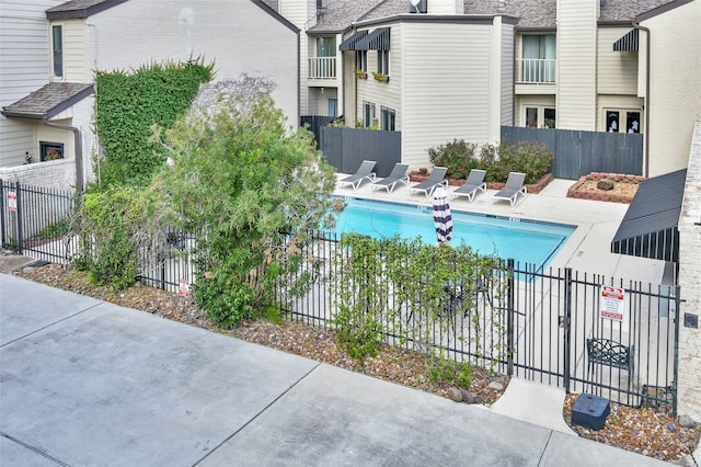 community pool with a patio and fence