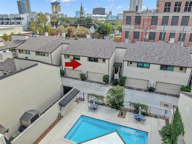 view of swimming pool featuring a view of city, a patio, and fence