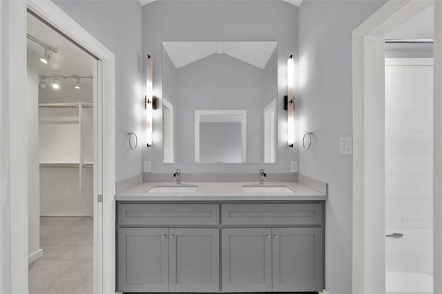 full bath with a sink, lofted ceiling, double vanity, and tile patterned flooring